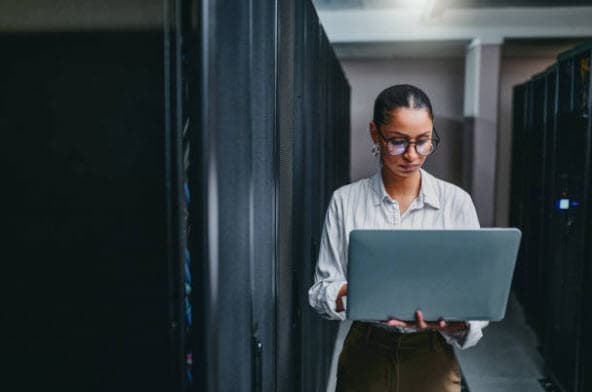 IT professional using a laptop in a server room