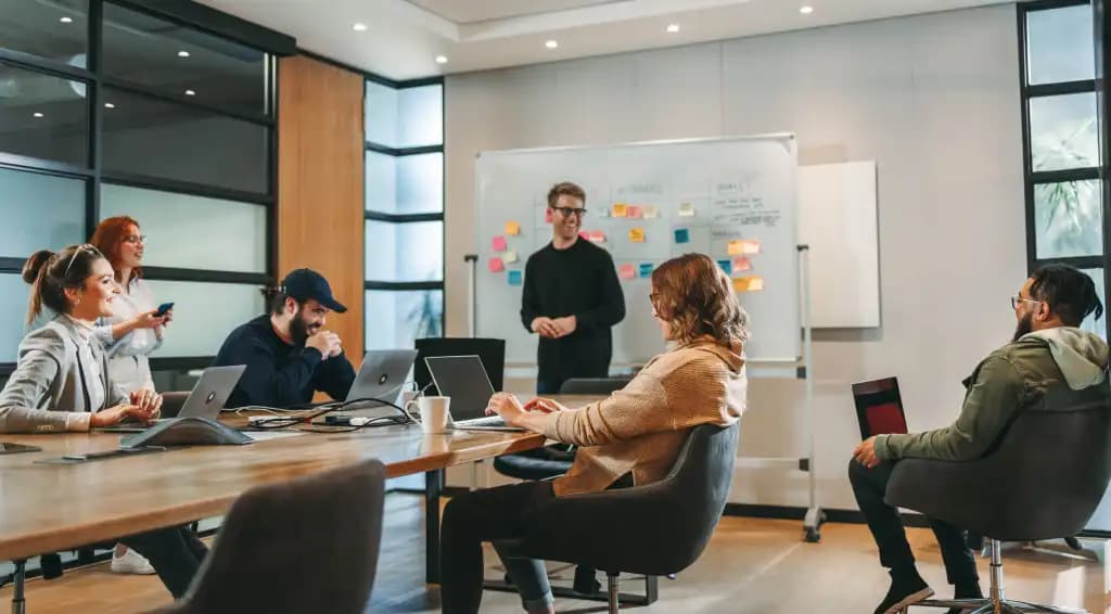 Colleagues meeting around a conference table with a whiteboard